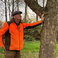 Ein Mann steht neben einem Baum.