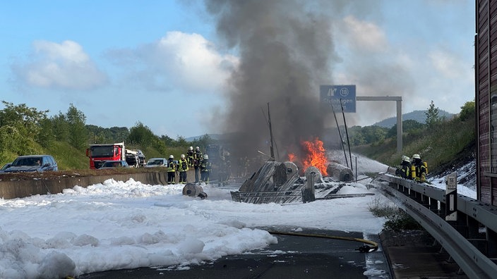 Überreste eines brennenden LKWs in einem Meer aus Löschschaum
