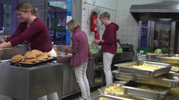 Drei Mitarbeiterinnen arbeiten in der Küche einer Gesamtschule