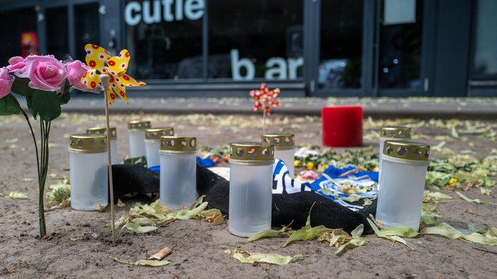 Eine kleine Gedenkstätte vor der Cutie Bar mit Blumen, Wundrädchen und Grabkerzen.