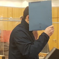 Ein Mann im Gericht hält sich einen Umschlag vors Gesicht
