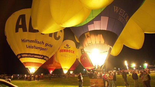 Das Bild zeigt einige Heißluftballone bei Nacht.