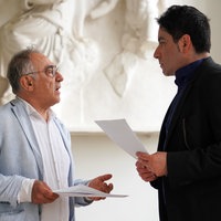 Das Bild zeigt zwei Herren mit Zetteln in der Hand, whährend eines Gesprächs