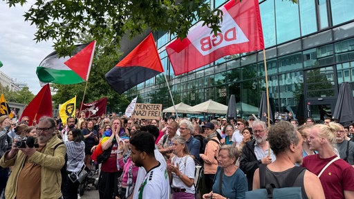 Eine Menschenmenge, einige halten Fahnen hoch, eine hat die Aufschrift "Münster nazifrei"