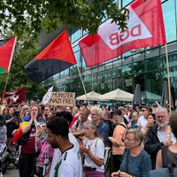 Eine Menschenmenge, einige halten Fahnen hoch, eine hat die Aufschrift "Münster nazifrei"