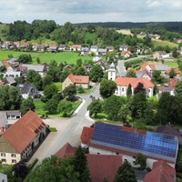 Ansicht vieler Häuser und einer Hauptstraße von oben. Auf einigen Dächern der Häuser sind Solar-Anlagen.