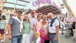 Eine Menschengruppe steht vor einer Achterbahn