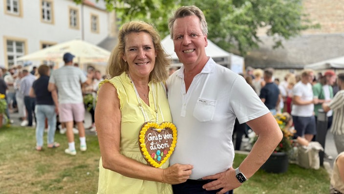 Ein Mann und eine Frau stehen lächelnd draußen auf einem Fest