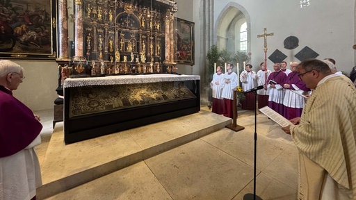 Mehrere Geistliche schauen auf einen mit Reliquien gefüllten Schrein