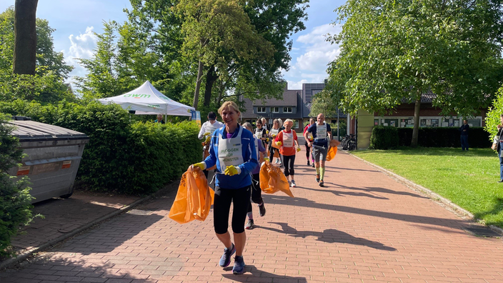 Teilnehmer:innen mit Mülltüten beim Lauf 