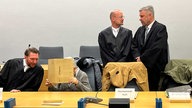 Verteidiger und die angeklagte Großmutter beim Prozessauftakt