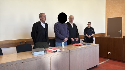 Der Angeklagte bei Prozessauftakt neben seinen Anwälten.