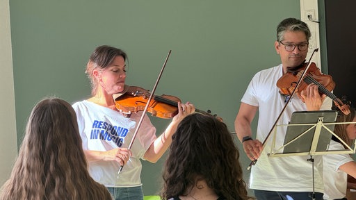 Rahel Rilling und Oliviero Hassan spielen vor Schülerinnen und Schülern Violine und Bratsche