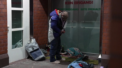 Ein Wohnungsloser hat einen Parka-Schlafsack genommen