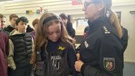 Schülerin probiert eine Polizeiuniform an