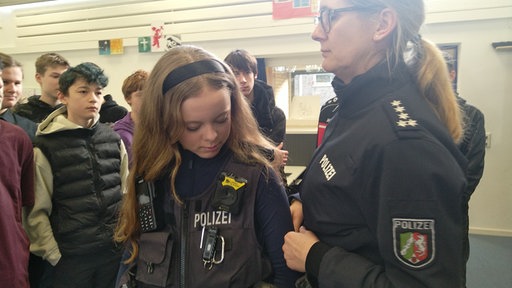 Schülerin probiert eine Polizeiuniform an