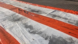 Eine beschmutzte rot-weiße Plane liegt auf dem Boden