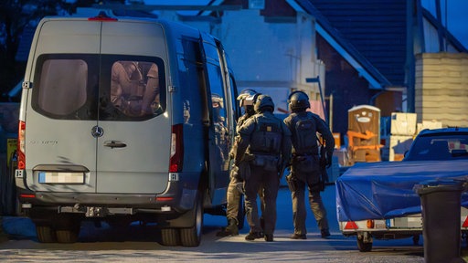 3 Beamte des SEK stehen um einen Sprinter