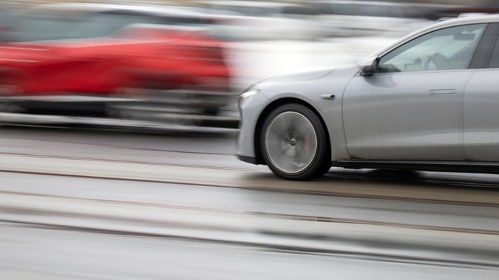 Ein graues Auto ist während der Fahrt verschwommen zu sehen, während es von einem roten Wagen überholt wird