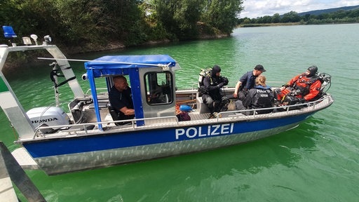 Polizeitaucher sitzen auf einem Sonarboot, das auf einem Kiesteich nahe Porta Westfalica treibt