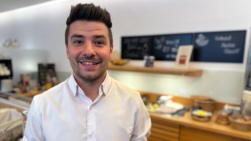 Marcel becker steht lächelnd vor einem Buffett