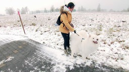 Eine Frau geht mit ihrem Hund im Schnee spazieren