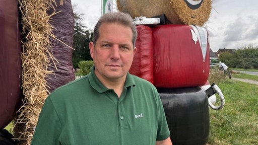 ein Mann vor zwei Strohballen-Puppen