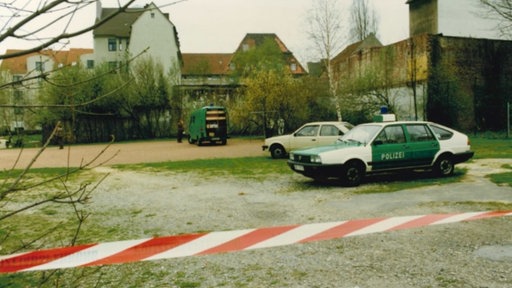 Der Tatort des Raubmordes an Eberhard Büker in 1990. Hinter einem Flatterband steht ein alter Polizeiwagen auf einem Spielplatz.
