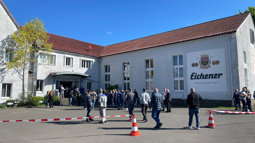 Menschen sammeln sich vor einem Thyssenkrupp-Gebäude