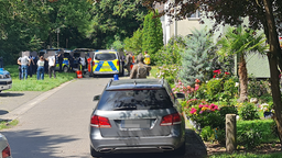 Eine Einfahrt mit Einsatzfahrzeugen, Polizeibeamten sowie weitere Personen, die um die Fahrzeuge stehen.