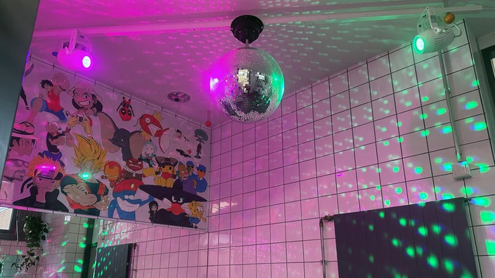 An der Decke einer öffentlichen Toilette hängt eine angestrahlte Discokugel
