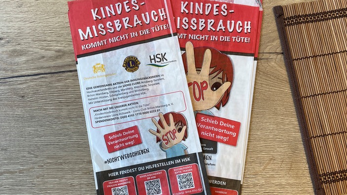 Zwei Bäckertüten liegen auf dem Tisch. Auf den Tüten steht u.a. "Kindesmissbrauch kommt nicht in die Tüte", eine Aktion gegen Kindesmissbrauch.