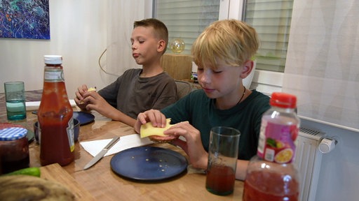 Zwei Jungen sitzen an einem Tisch und essen etwas