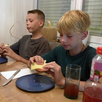Zwei Jungen sitzen an einem Tisch und essen etwas