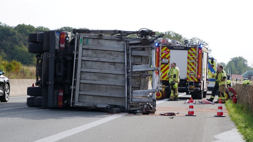 Heckansicht des umgekippten Lkws auf der A33. Die Feuerwehr ist vor Ort.