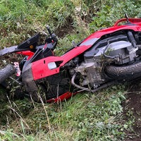 Ein rotes dreirädriges Motorad liegt auf einem Wiesenstück.