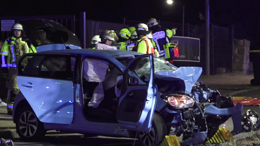 Einsatzkräfte am schwerbeschädigten Auto