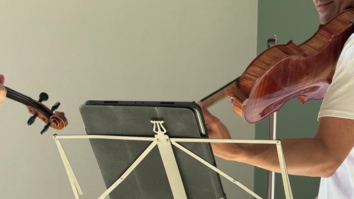 Eine Bratsche wird gespielt, davor ein Notenständer mit Notenheft