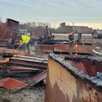 Zwei Männer bearbeiten Metallteile mit Schweißgeräten auf einer Baustelle