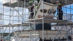 Zwei Männer arbeiten auf einem Baugerüst
