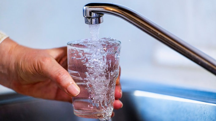 Wasser aus einem Wasserhahn fliesst in ein Glas