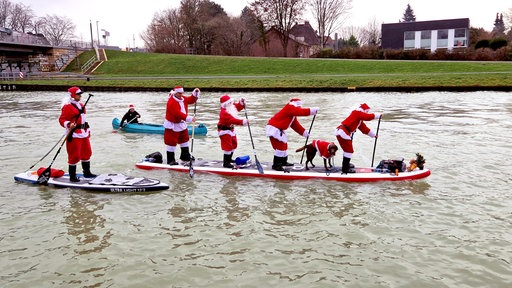 Fünf Stand-Up-Paddler in Weihnachtsmannkostümen auf dem Dortmund-Ems-Kanal