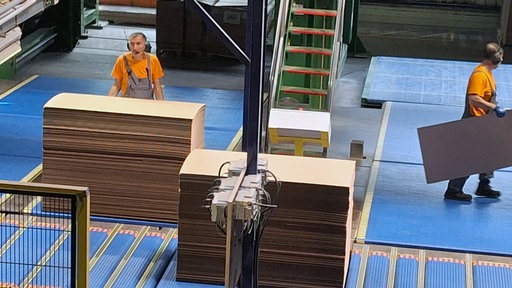 Mitarbeiter der Herforder Pappenhersteller lagern Pappe in einer Halle um.