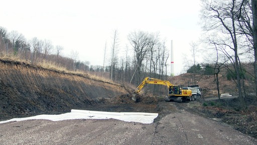 Eine Baustelle im Wald vor einem im Bau befindlichen Windrad