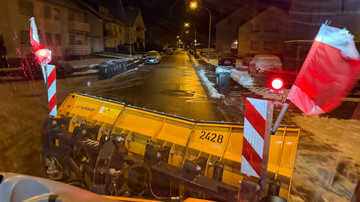 Ein Streufahrzeug fährt am frühen Morgen eine Straße entlang.