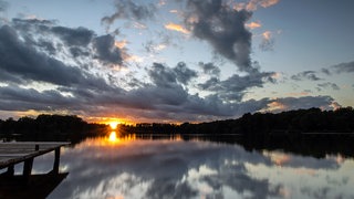 Ein See mit einem Holzsteg im Sonnenuntergang