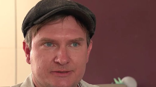 Porträt eines Mannes mit blauen Augen, dunkelblonden Haaren und einer Mütze
