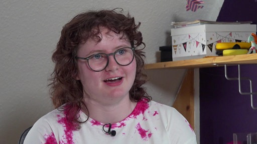 Porträt einer jungen Frau mit blauen Augen, braunen Locken und einer Brille