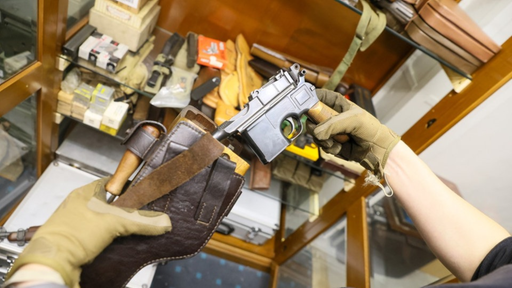 Waffe wird aus Leder- Holster gezogen, Hände mit Arbeitshandschuhen