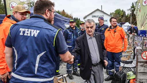 Herbert Reul, Innenminister (CDU), spricht mit Helfern des THW an der deutsch belgischen Grenze an einer Wassertankstation